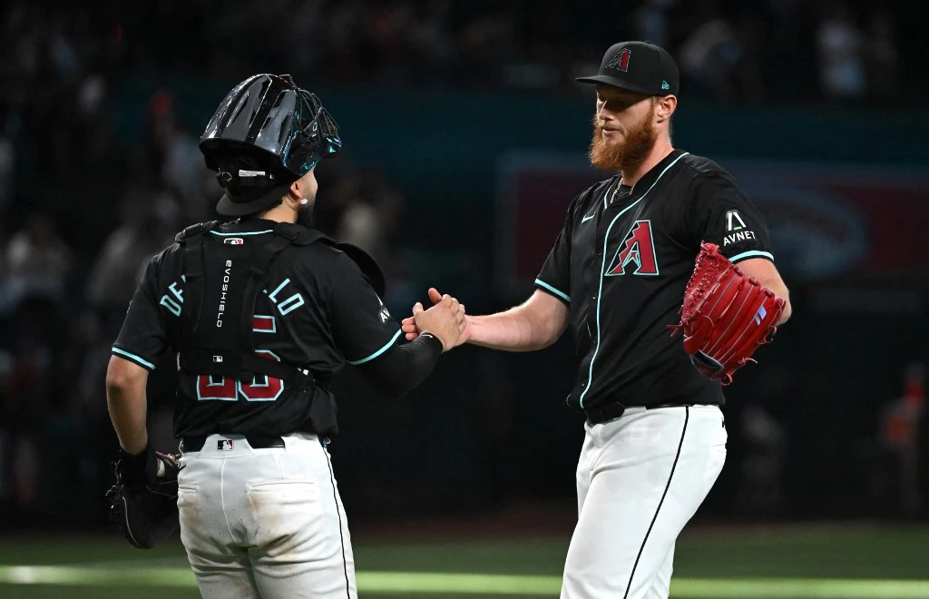 AJ Puk #33 and Adrian Del Castillo #25 of the Arizona Diamondbacks celebrate an 11-4 win against the Colorado Rockies at Chase Field on August 14, 2024 in Phoenix, Arizona.